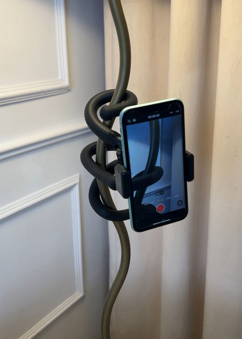 Phone holder with a coiled black cable against a light-colored wall.